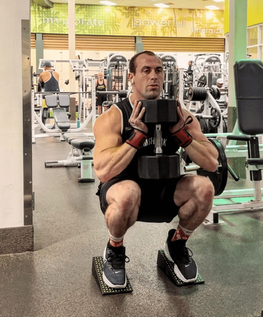 Athlete performing squats with Flexelent squat wedges during gym workout.