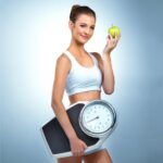 Woman holding a scale and apple as part of healthy lifestyle tips