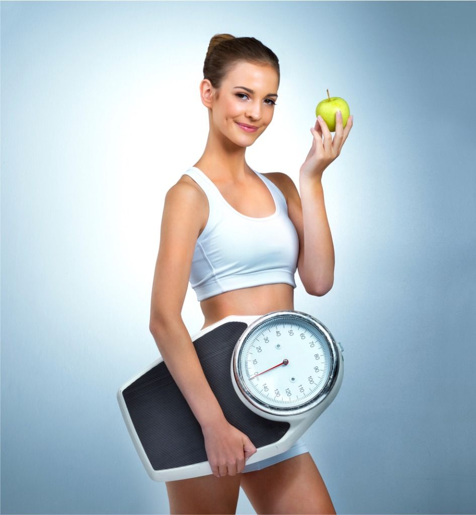 Woman holding a scale and apple as part of healthy lifestyle tips