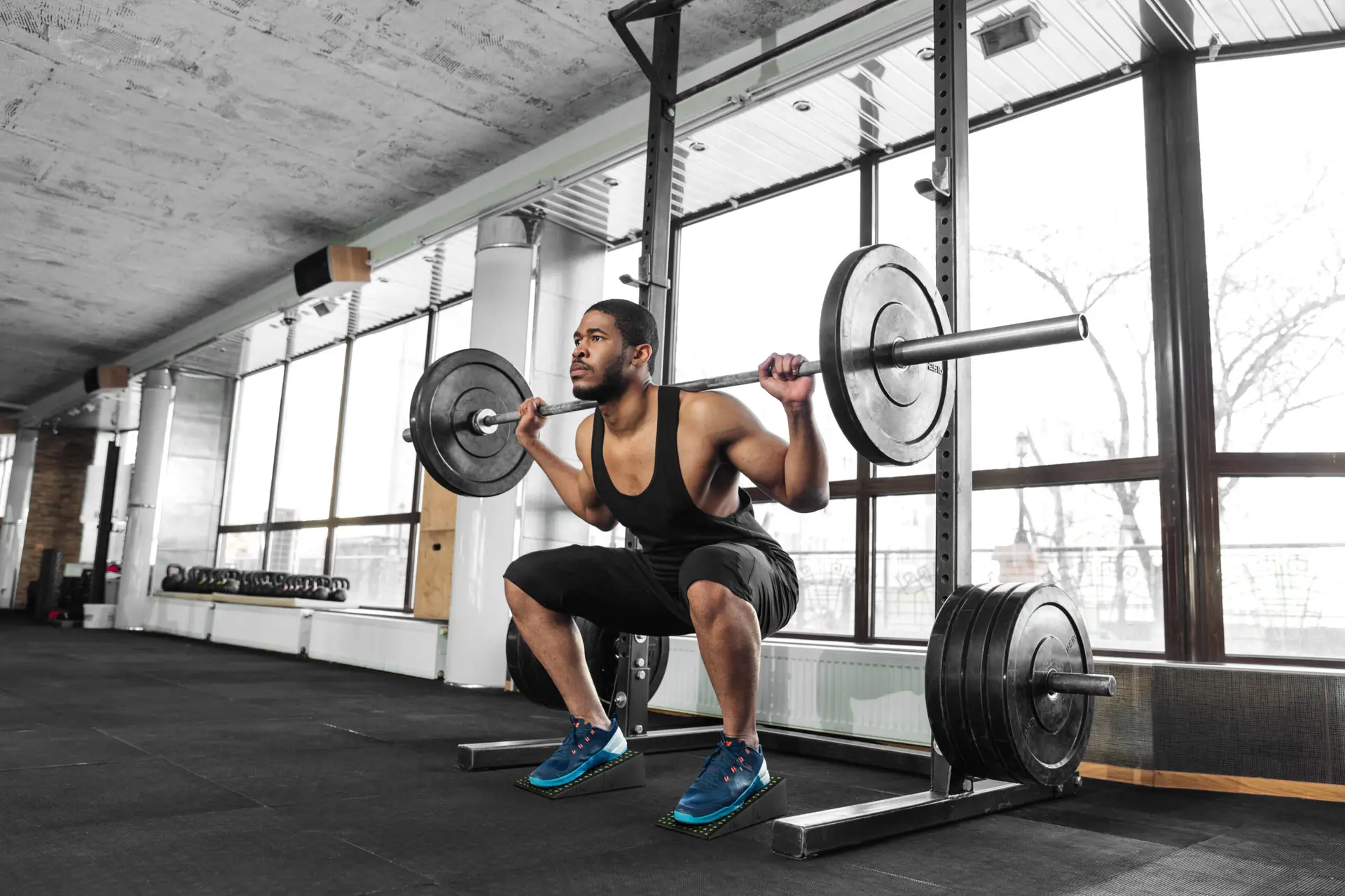 Workout tips: Man performing a barbell squat with Flexelent squat wedges for better form and mobility.