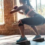 Woman performing squats with Flexelent squat wedges to enhance workout form