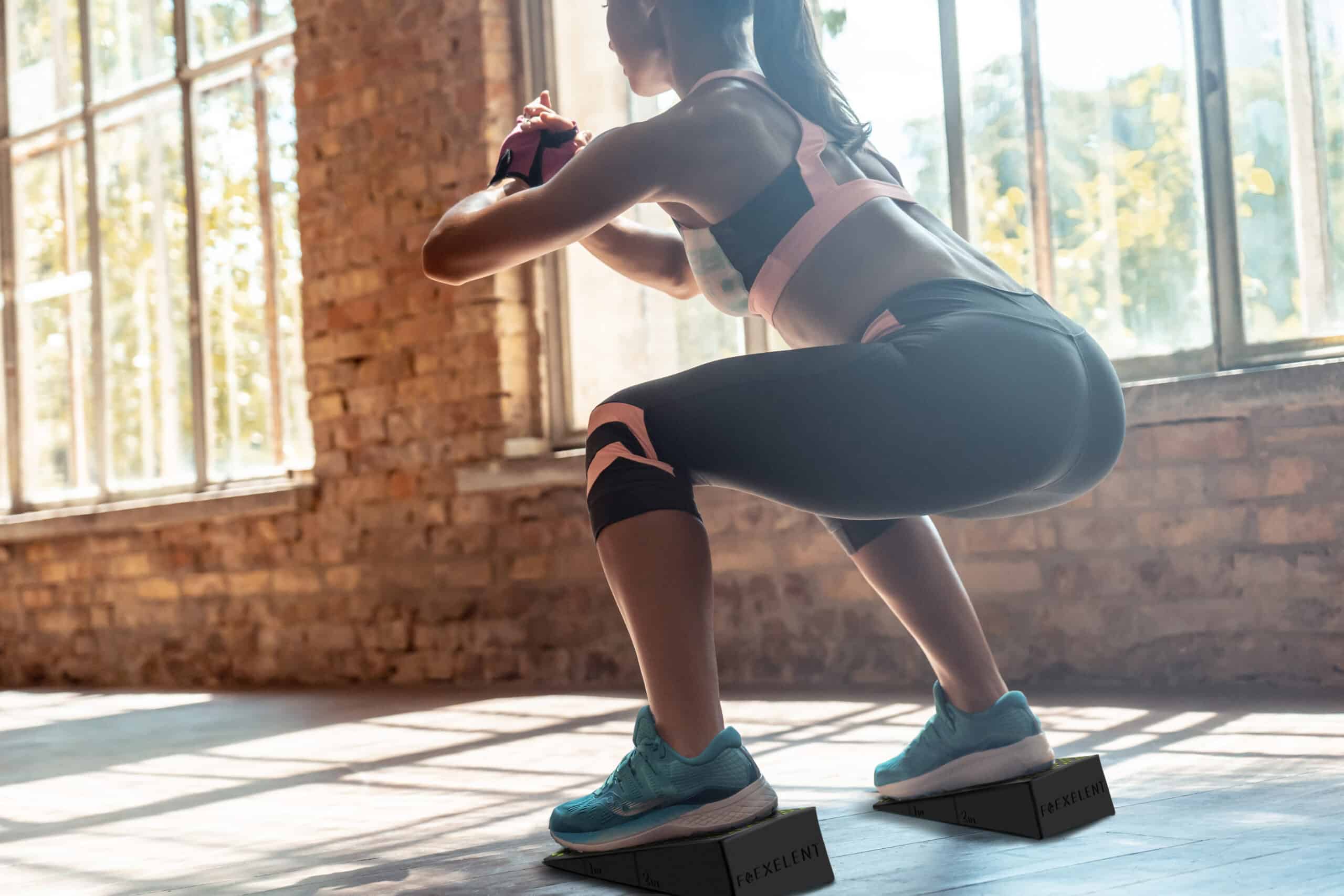 Woman performing squats with Flexelent squat wedges to enhance workout form